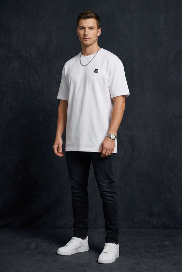 Man wearing WEARON Logo Patch Tee in White with black denim, full body, dark studio backdrop.