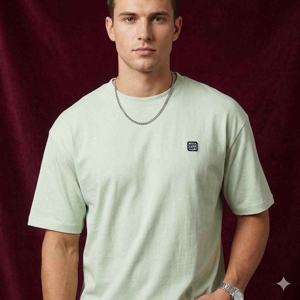 Close-up of WEARON Logo Patch Tee in Sage on model, deep burgundy velvet backdrop.