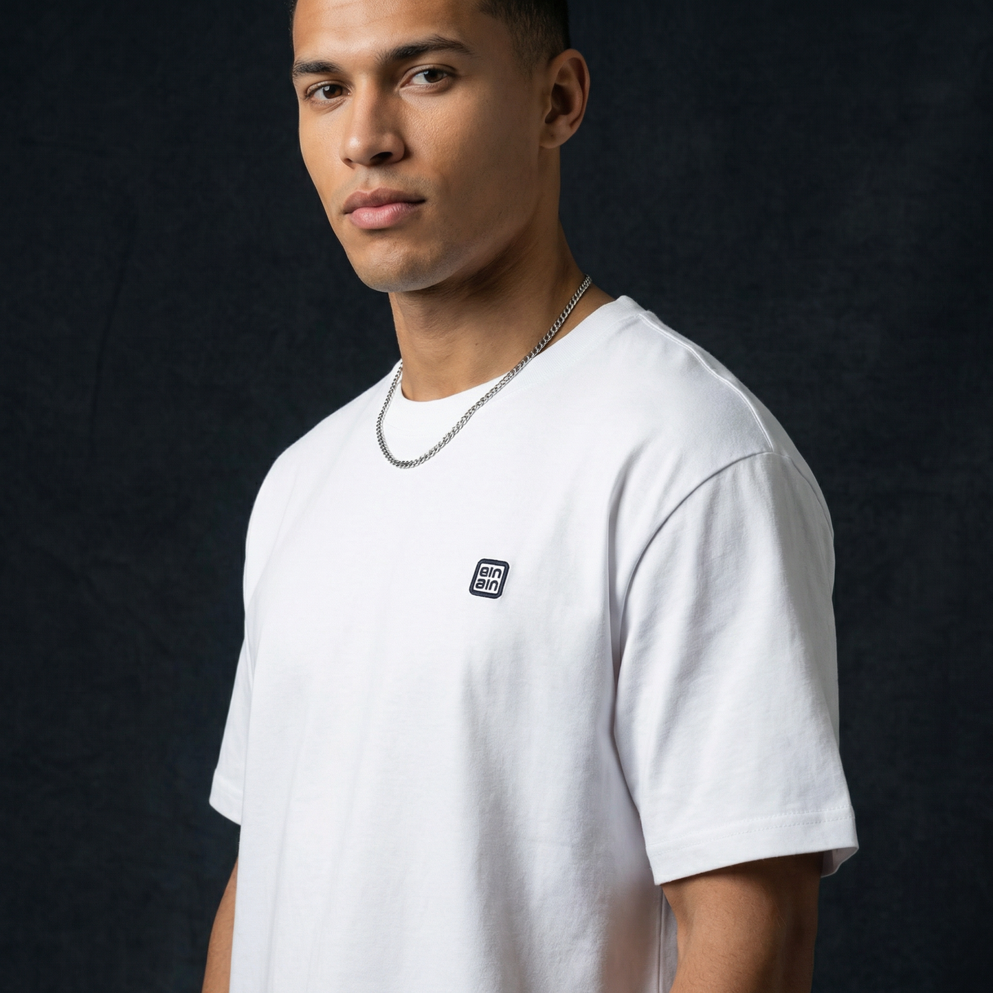 Close-up of WEARON Logo Patch Tee in White showing chest woven logo emblem.