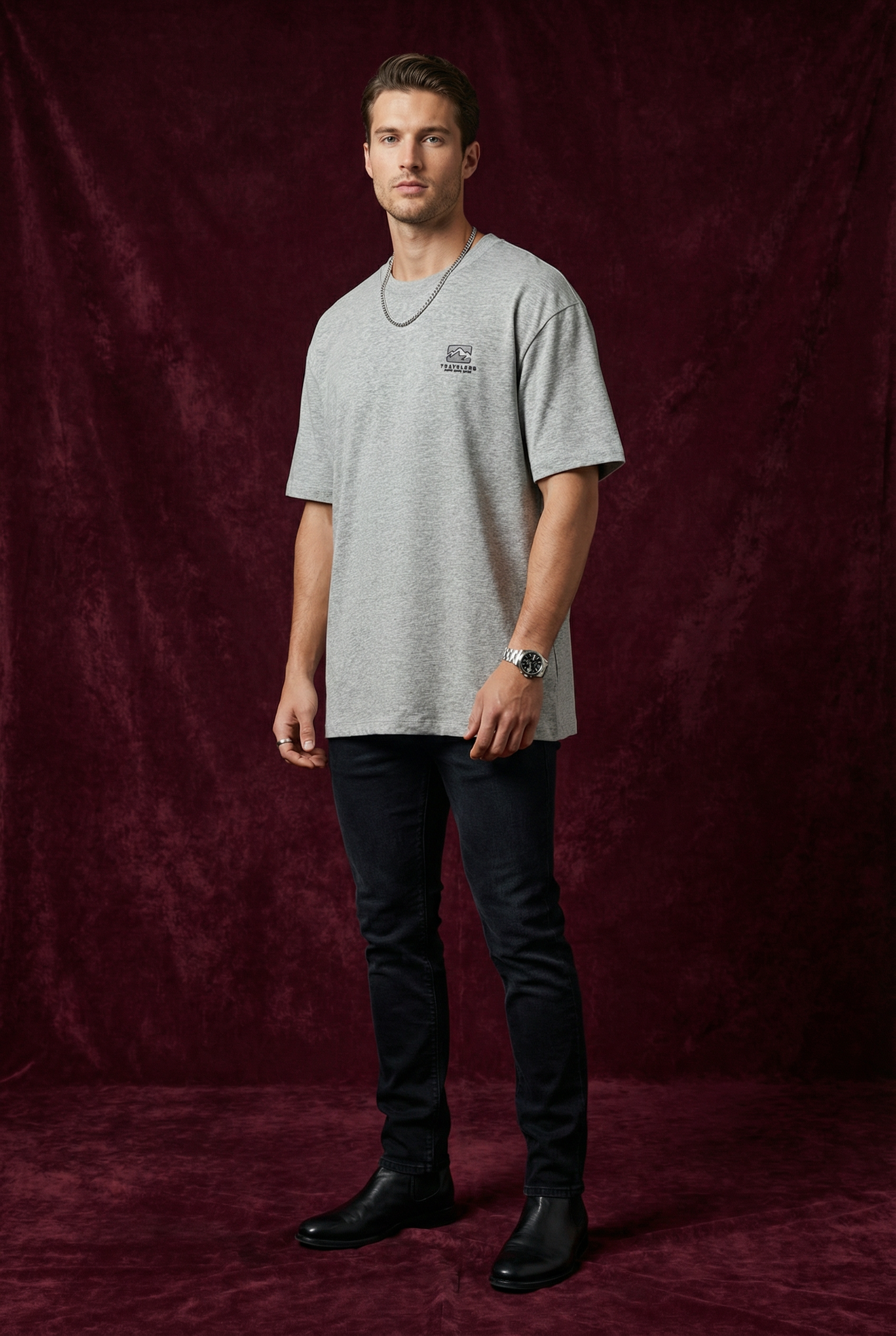 Man wearing WEARON Travelers Mountain Tee in Heather Gray, full body, deep burgundy velvet backdrop.