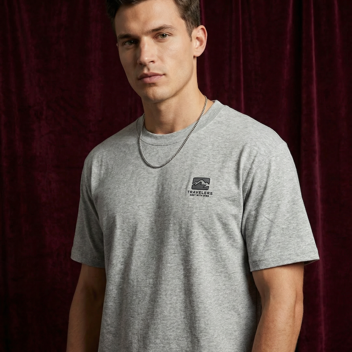 Close-up of WEARON Travelers Mountain Tee in Heather Gray showing chest mountain logo print, burgundy velvet backdrop.