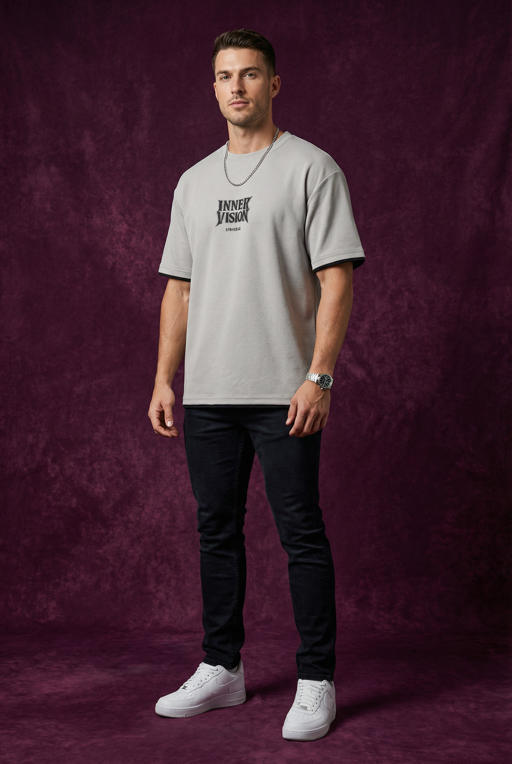 Man wearing WEARON Inner Vision Tee in Gray with cream chest typographic print, burgundy backdrop, full body.