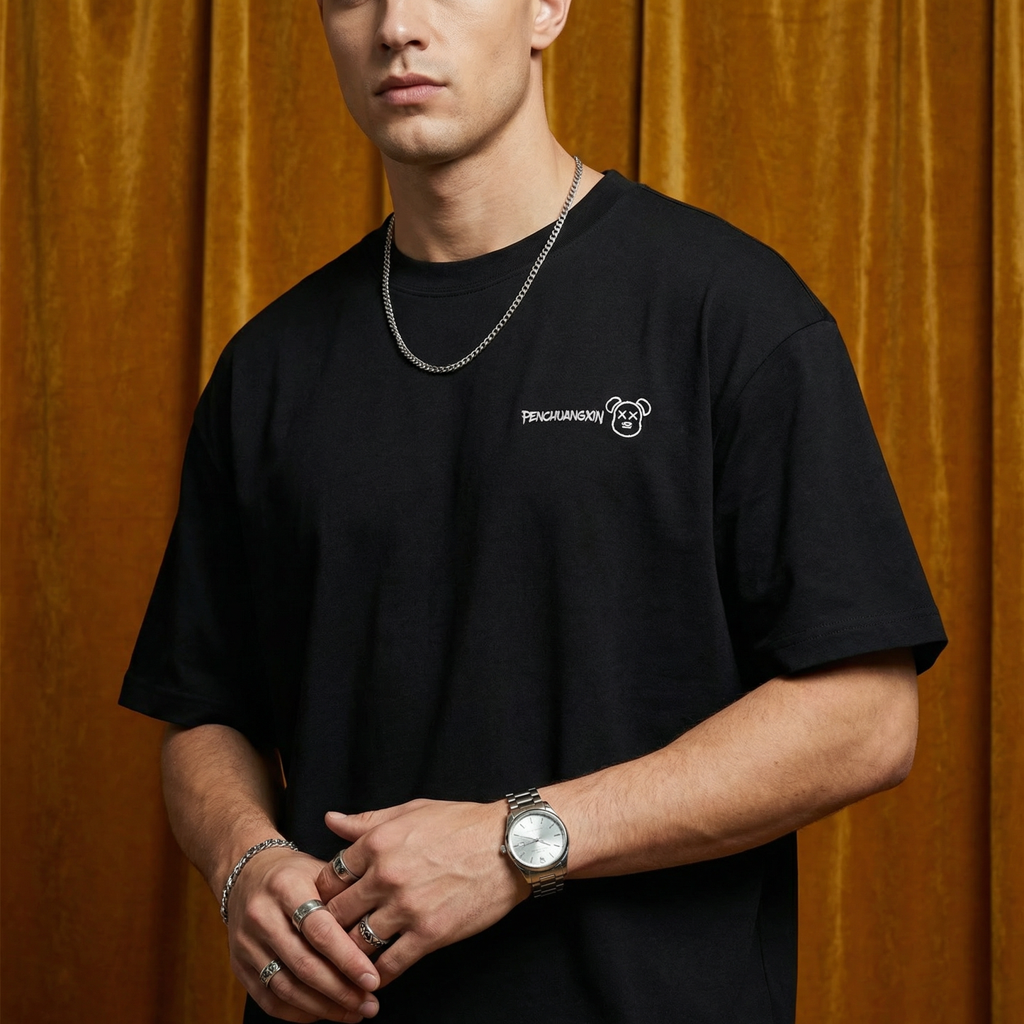 Close-up of WEARON Bear Patch Tee in Black with embroidered bear motif, golden velvet backdrop.