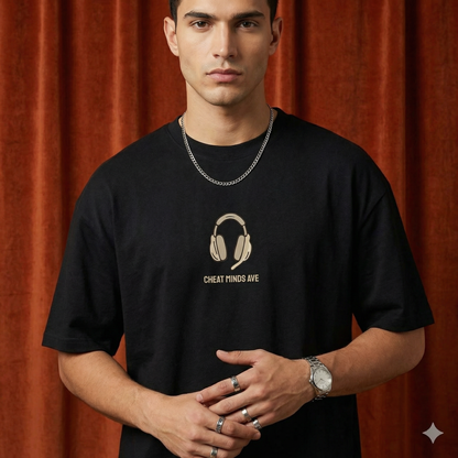 Close-up of WEARON Headphones Tee in Black with illustrated headphones motif, rust velvet backdrop.