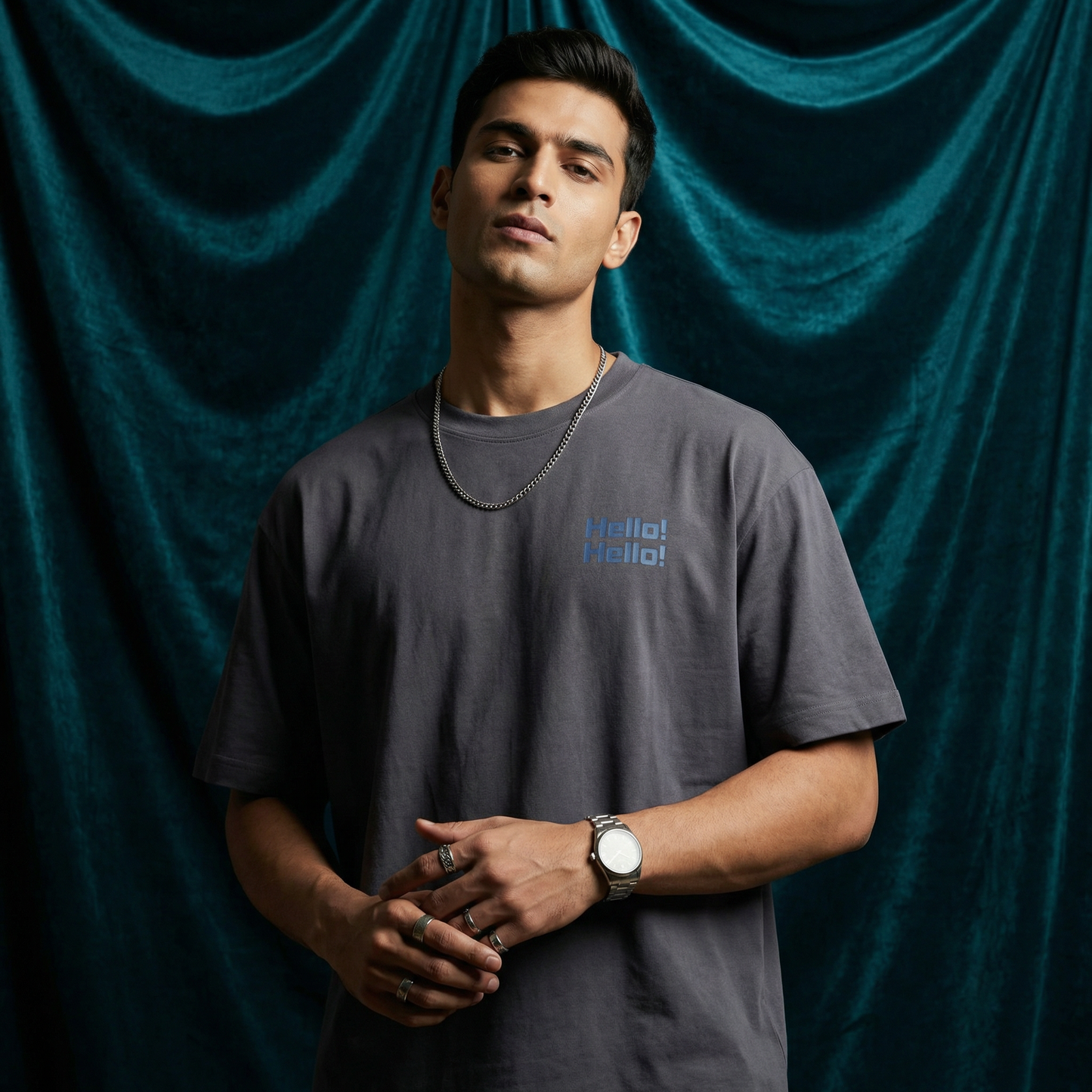 Close-up of WEARON Hello Tee in Charcoal with chest 'Hello! Hello!' print, deep teal velvet backdrop.