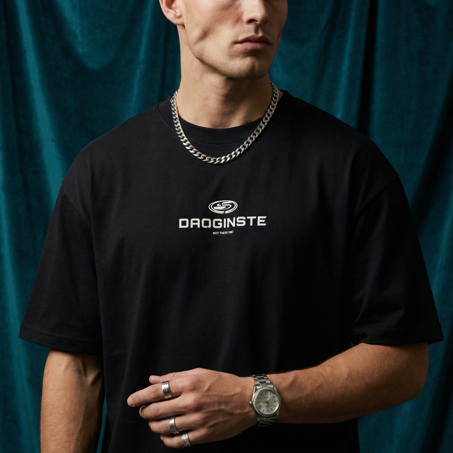 Close-up of WEARON Sport Logo Tee in Black with chest sport emblem print, deep teal velvet backdrop.