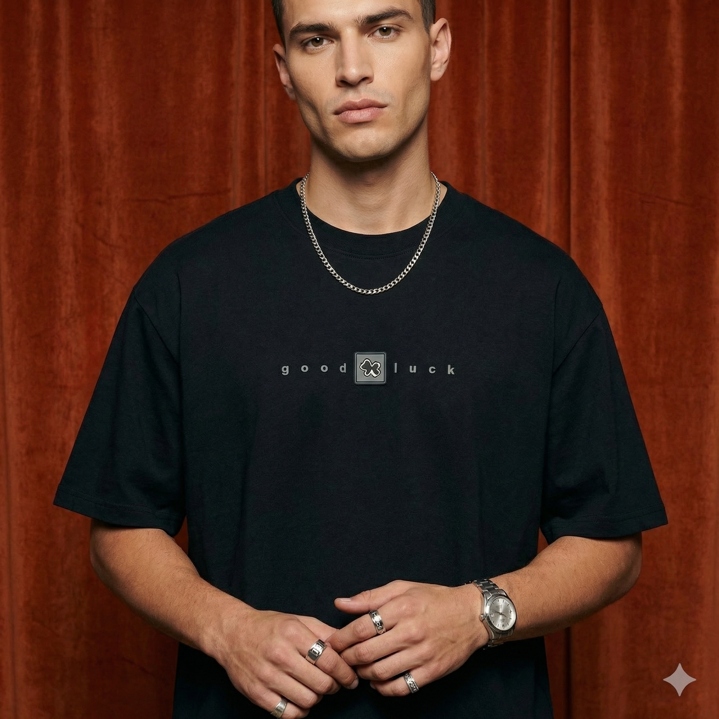 Close-up of WEARON Good Luck Tee in Black with chest 'good luck' typography, rust velvet backdrop.