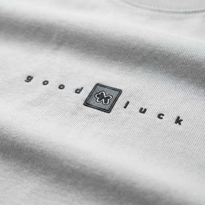 Macro detail of 'good luck' chest typography on White cotton tee.