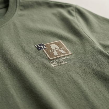 Macro detail of woven chest patch on Sage cotton tee.