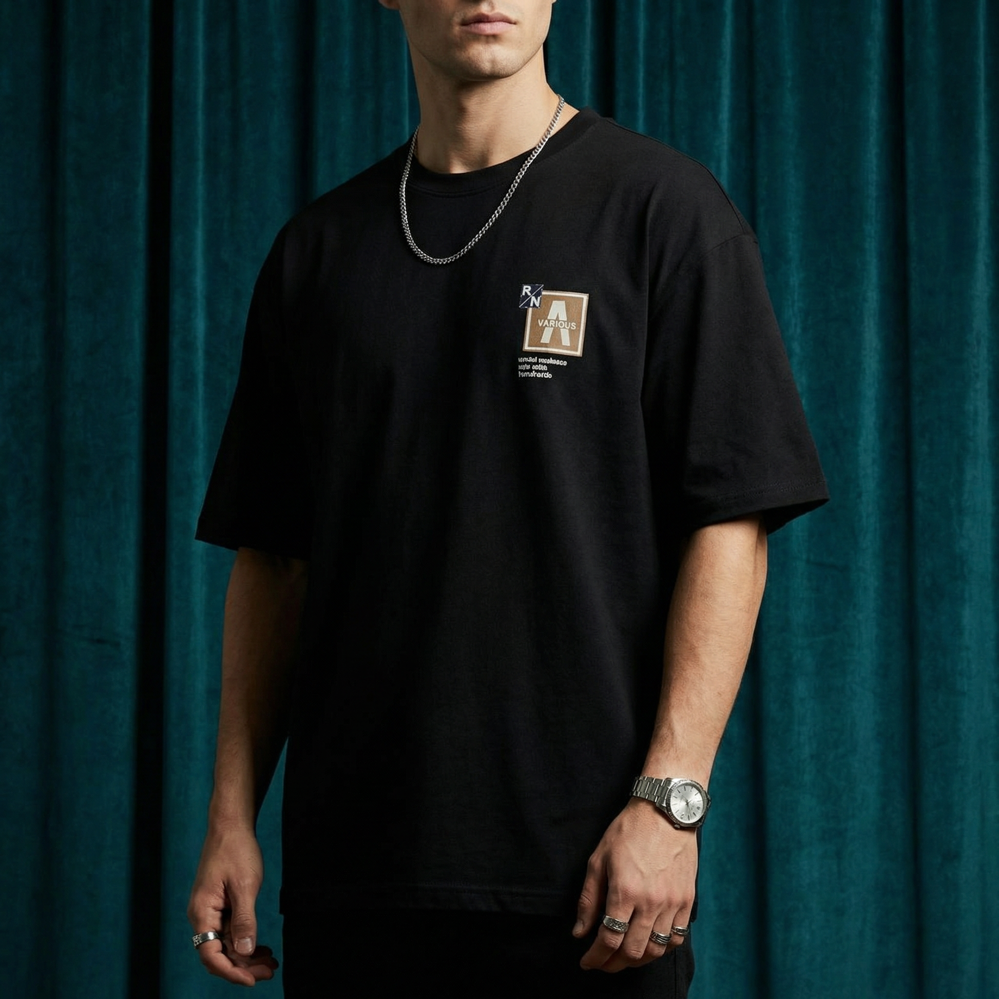 Close-up of WEARON Patch Detail Tee in White showing woven chest patch, deep green velvet backdrop.