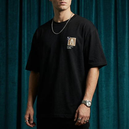 Close-up of WEARON Patch Detail Tee in White showing woven chest patch, deep green velvet backdrop.
