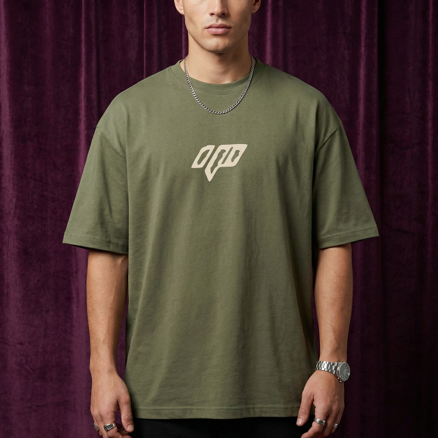 Close-up of WEARON Geometric Logo Tee in Black with chest geometric emblem, rust velvet backdrop.