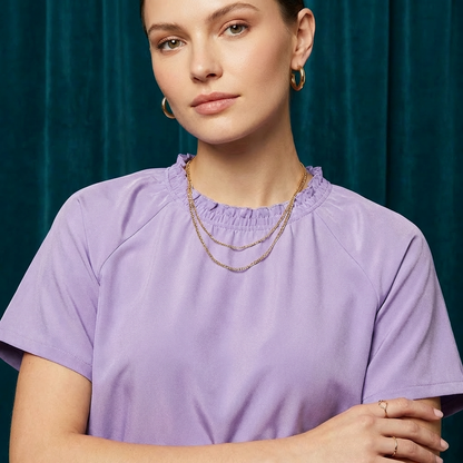 Close-up of WEARON Smocked Satin Top in Lavender with smocked neckline detail, deep teal velvet backdrop.