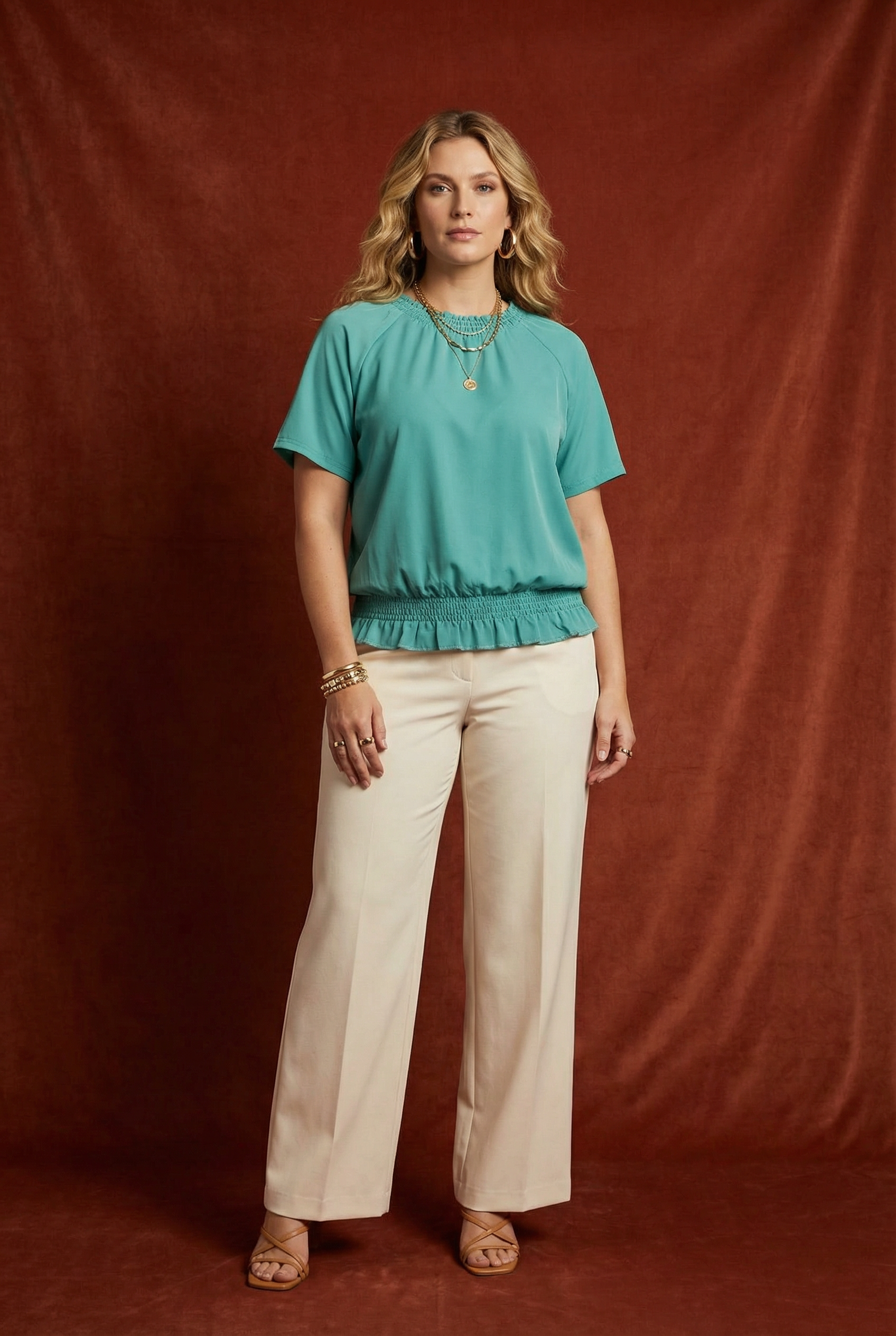 Woman wearing WEARON Smocked Satin Top in Teal with cream wide-leg trousers, deep rust velvet backdrop.