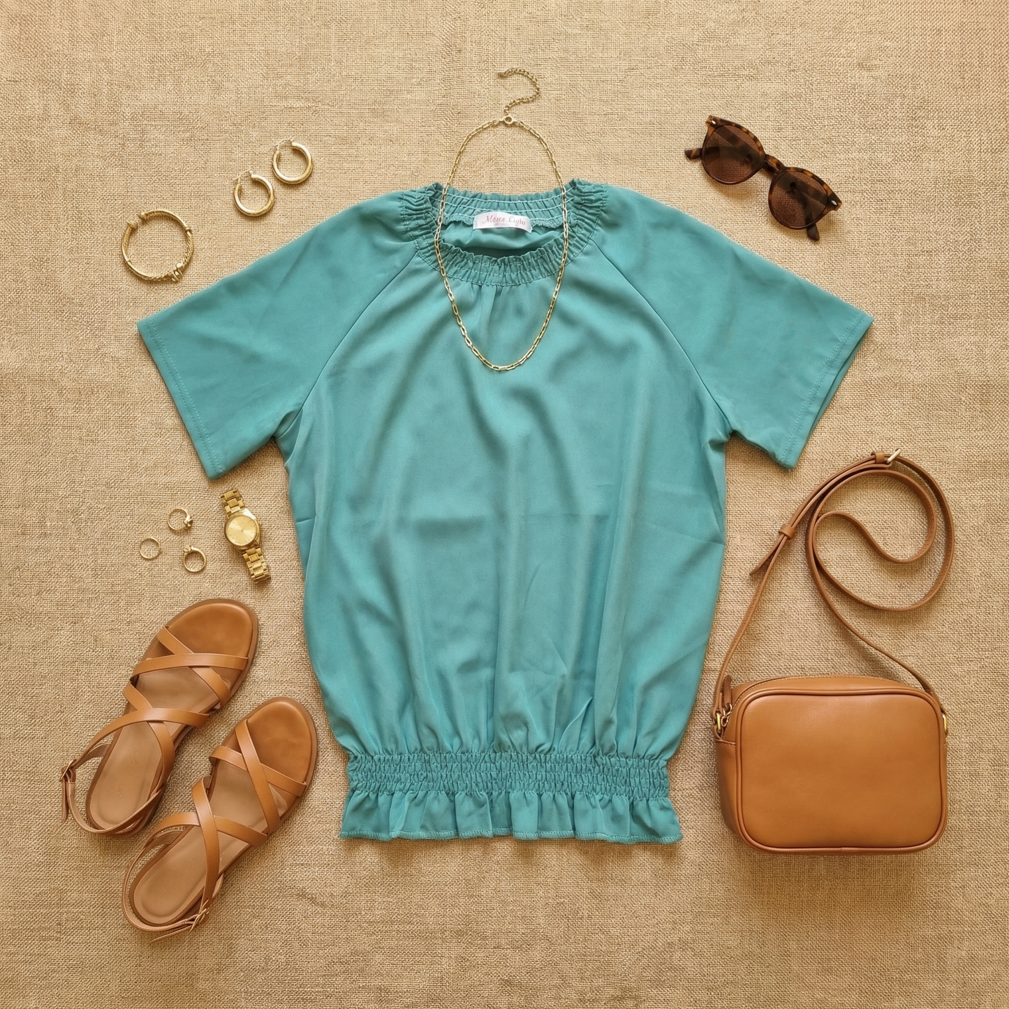 Flat lay of WEARON Smocked Satin Top in Teal styled with tan crossbody bag, gold sandals, and gold jewellery.
