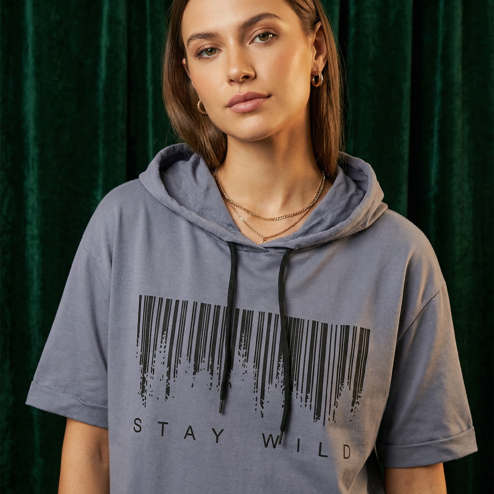 Close-up of WEARON Short-Sleeve Hoodie Tee in Gray with Stay Wild barcode graphic, deep green velvet backdrop.