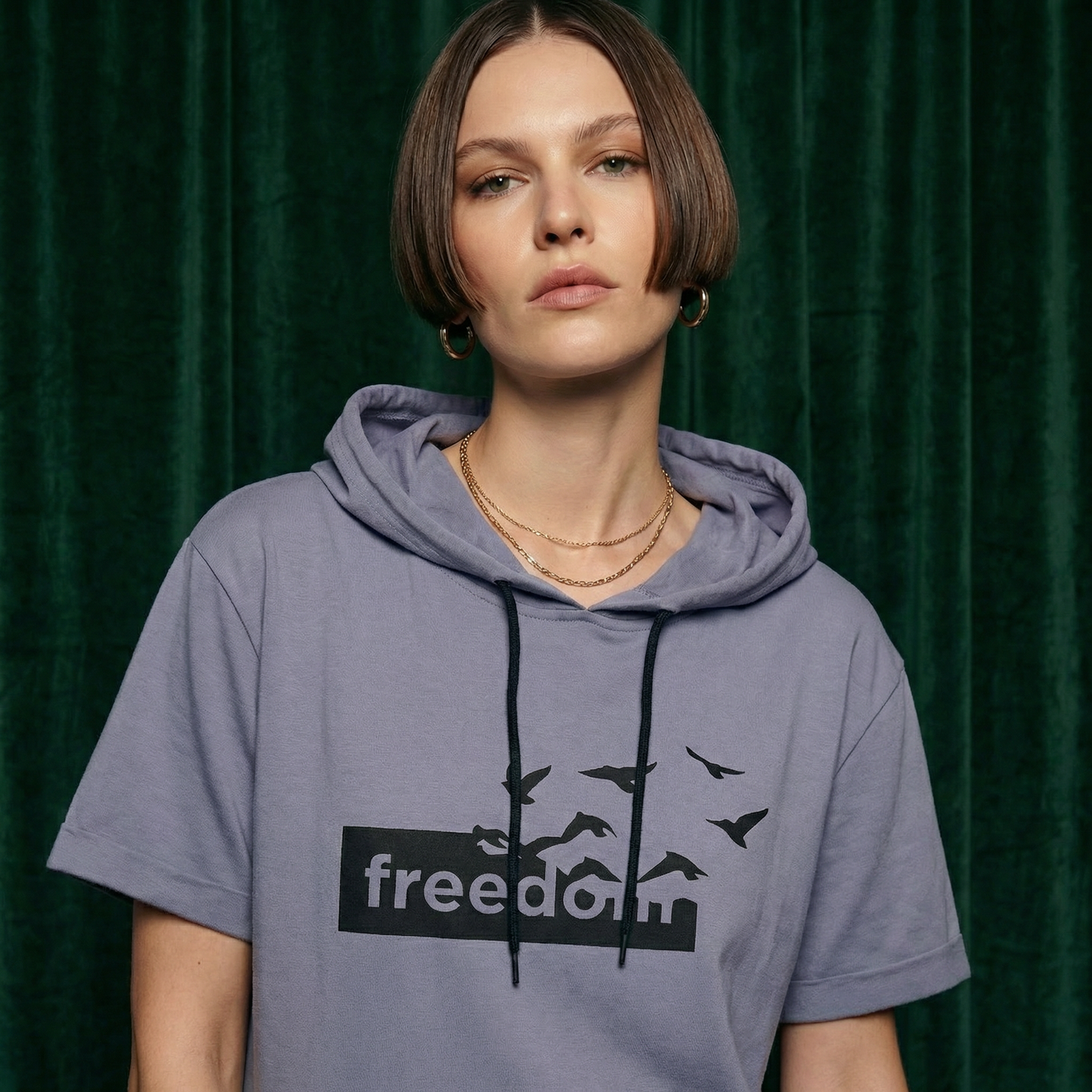 Close-up of WEARON Short-Sleeve Hoodie Tee in Lavender with Freedom birds graphic, deep green velvet backdrop.