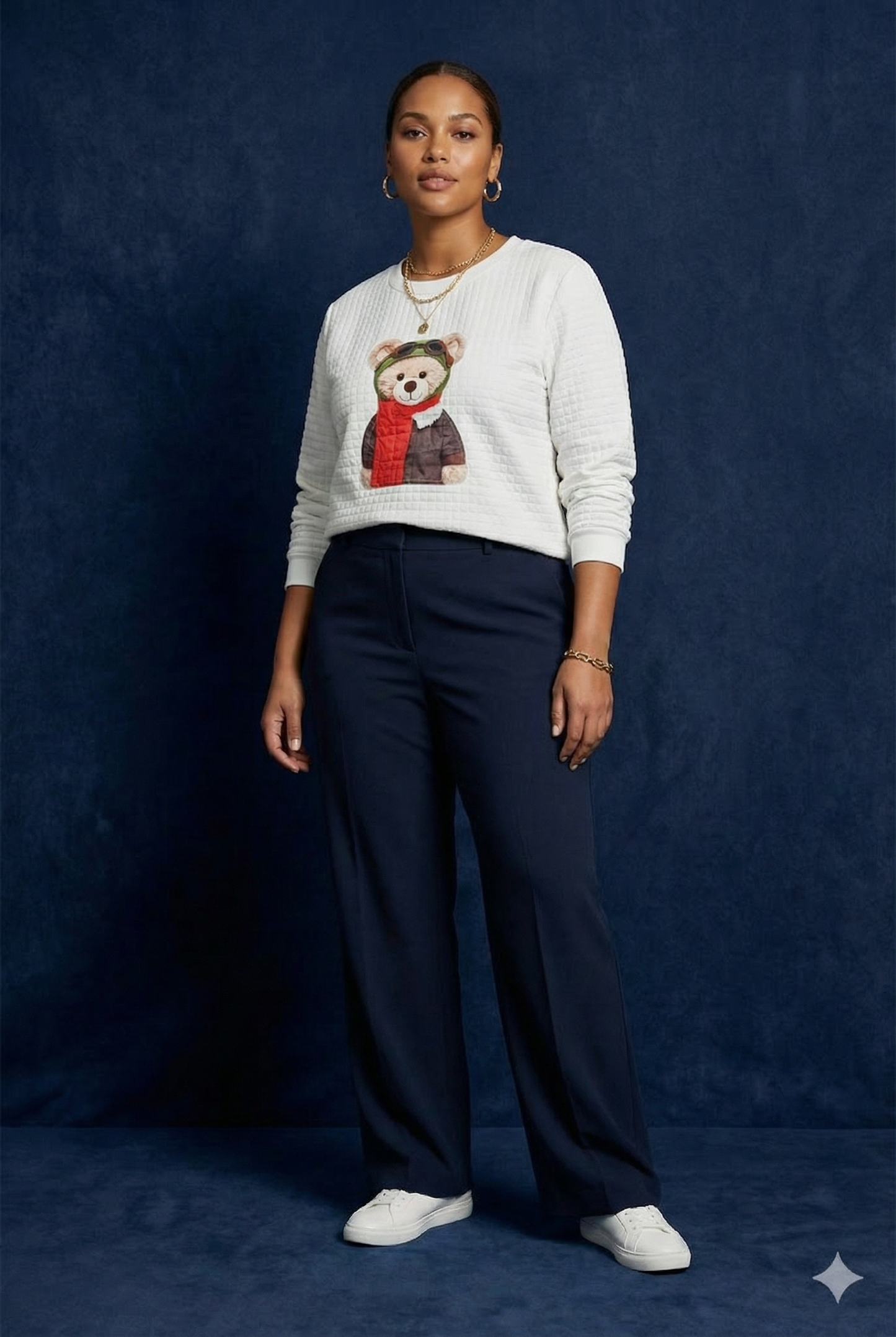 Full body view of WEARON Teddy Bear Quilted Sweatshirt with Aviator pilot teddy graphic, navy trousers, deep blue backdrop.