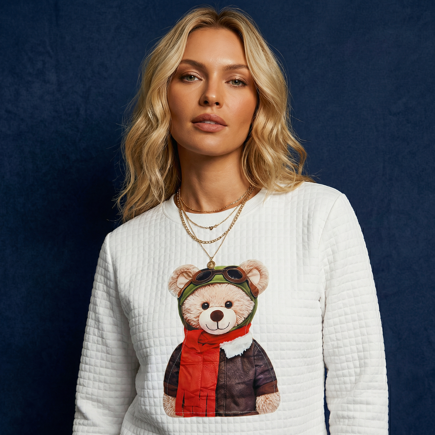 Close-up of WEARON Teddy Bear Quilted Sweatshirt with Aviator pilot teddy graphic, deep blue velvet backdrop.