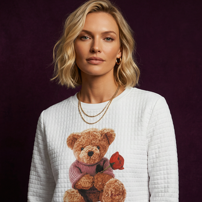 Close-up of WEARON Teddy Bear Quilted Sweatshirt with Rose-bearing teddy graphic, deep purple velvet backdrop.