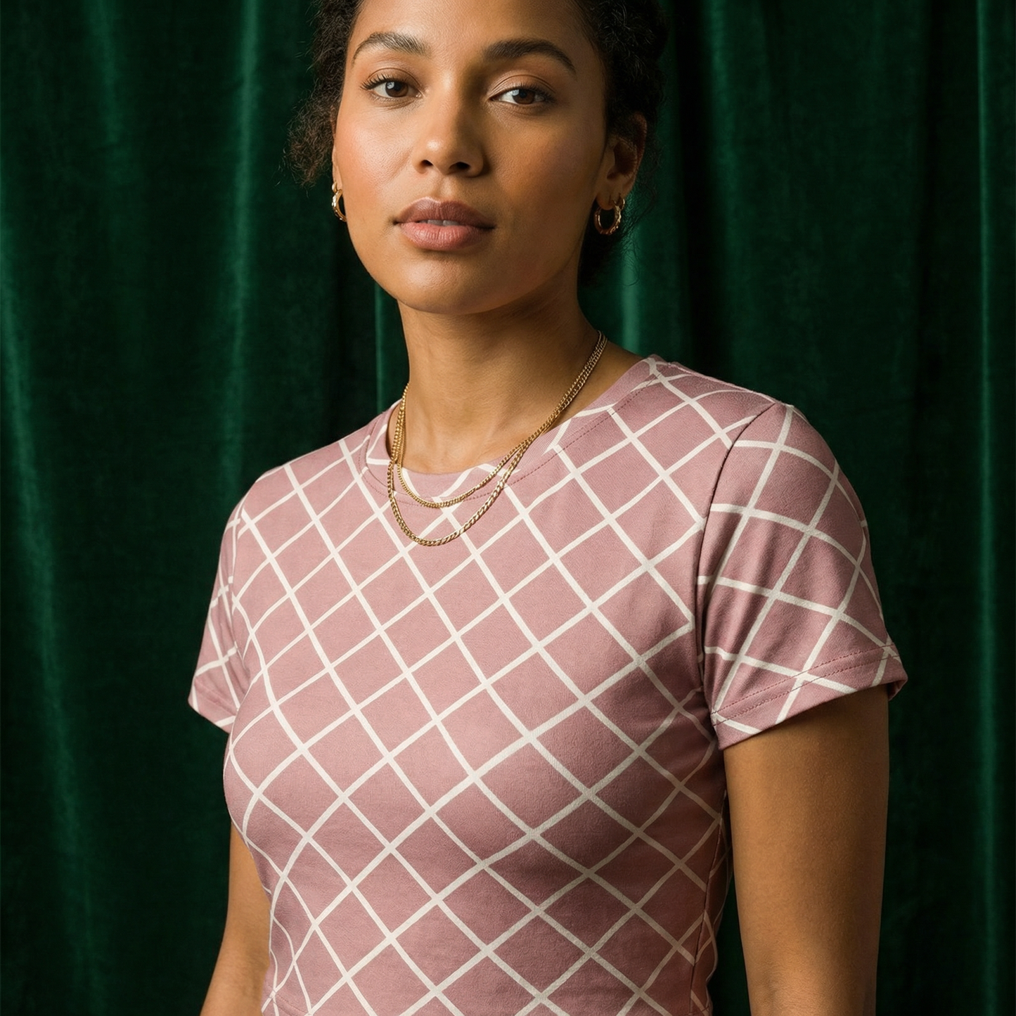 Close-up of WEARON Diamond Lattice Tee in Rose with cream bias-set windowpane lattice print, deep green velvet backdrop.